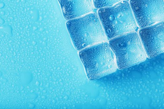 Ice made of cubes lined up with drops on a blue background