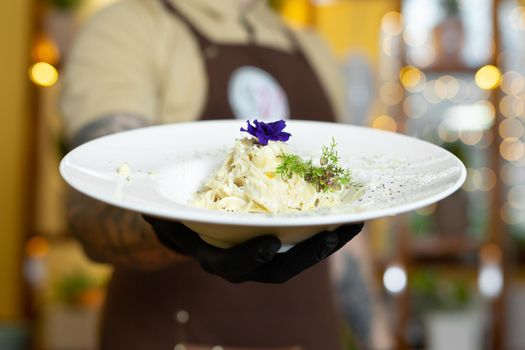 Pasta with cream and parmesan, decorated with edible flowers and microgreen close-up