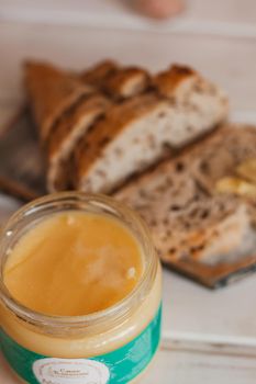 Ghee butter in glass jar and sliced bread on table. Healthy eating, breakfast