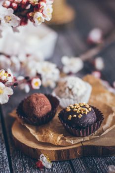 Spring collection of handmade chocolate bonbons candies and cherry flowers decoration on rustic wooden background