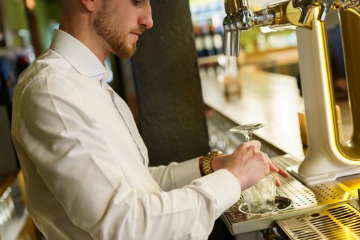 Crop barman pouring beer in glass in a bar