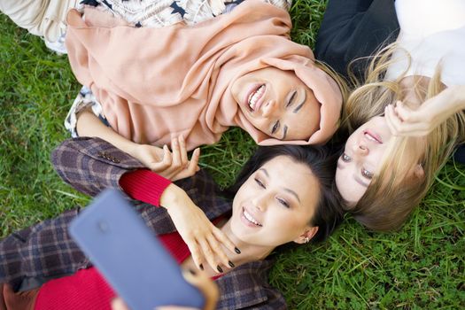 Multiracial women taking selfie together in park