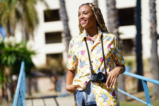 Smiling black woman with photo camera in city