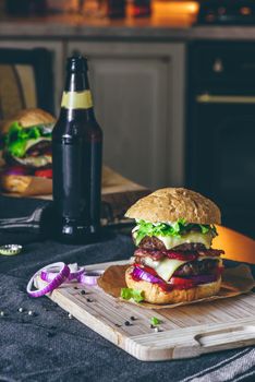 Prepared Cheeseburger on Cutting Board with Bottle of Beer on T
