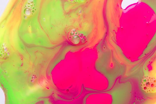 Liquid fluorescent pink and green paints background with bubbles. Abstract print