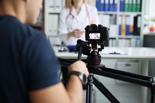 Photographer filming doctor on camera using tripod and slider closeup