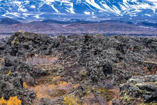 Vast lava field with snow covered mountains in the background