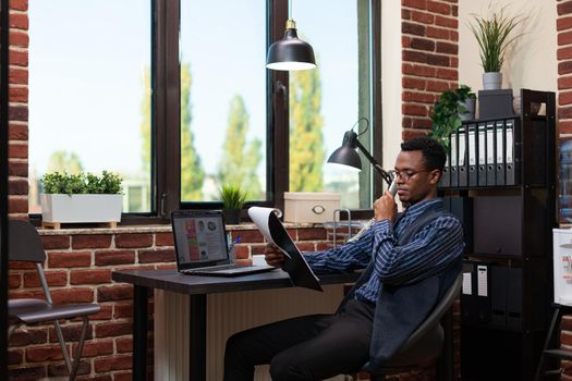 Wide angle portrait of african american startup owner with glasses analyzing marketing indicators