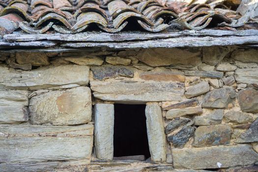 Old stone window, slate roof and stone wall