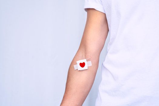 Blood donation concept with copy space. Blood donor with bandage after giving blood on a white background