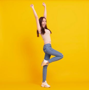 Happy Asian girl dancing and celebrating isolated over yellow