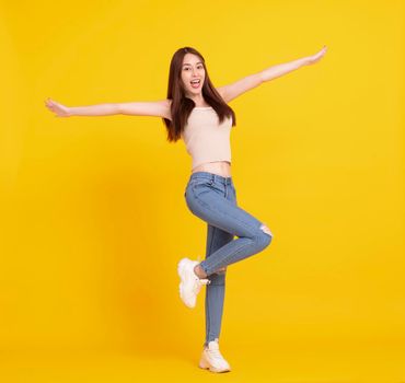 Happy Asian girl jumping and celebrating isolated over yellow