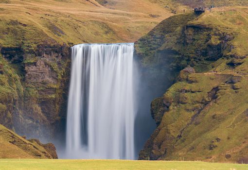Long exposure, Skogafoss waterfall from the distance with hikers on top viewpoint