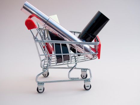 Front view of a shopping cart with makeup products on a pink background. Cosmetic shopping concept.