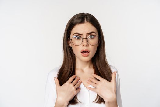 Close up of shocked, insulted woman in glasses, looking hurt and confused, standing over white background