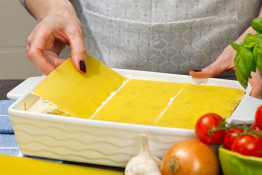 Woman preparing meat lasagna in kitchen. lasagna recipe - Italian food