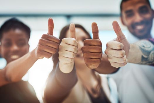 Go get that success. Cropped shot of a team of colleagues showing thumbs up at work.