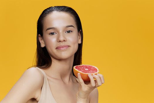 young woman eating grapefruit in hands smile vitamins diet yellow background
