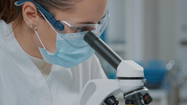 Specialist analyzing dna on microscope in laboratory