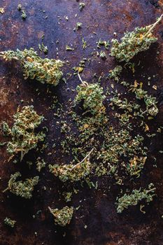 medical cannabis buds are scattered randomly on a rusty metal surface