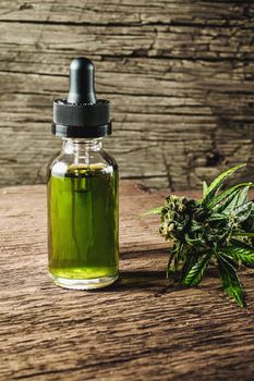 Glass bottle with herbal organic medicine CBD concentrate, droplet dosing a biological and ecological hemp plant herbal pharmaceutical cbd oil from a jar and medical cannabis bud on wooden background