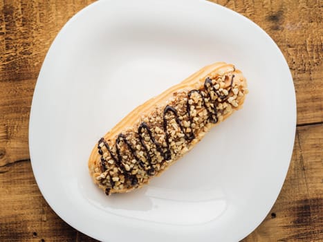 eclair on a white plate on wooden background