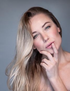 Closeup Portrait of a Beautiful Blond Woman Isolated on Gray Background. Fashion Girl with Natural Makeup and with Perfect Young Complexion.