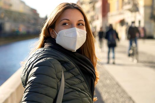 Portrait of casual woman with KN95 FFP2 protective mask turns around and staring away in the city