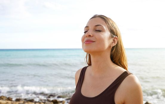 Young woman on the beach taking deep breath enjoying fresh air freedom