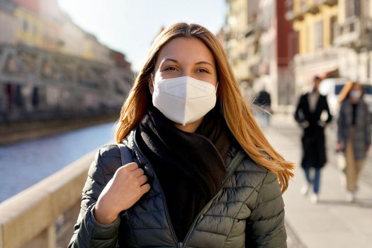 Beauty fashion girl wearing protective face mask walking in city street on sunset