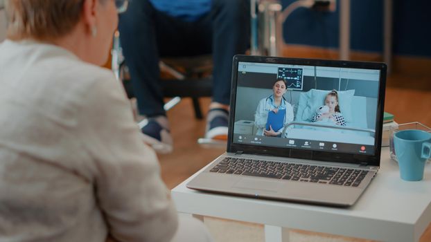 Retired adult using videoconference on laptop to attend online meeting