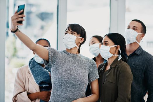 Dont let corona compromise your camaraderie. Shot of a group of young people wearing masks and taking selfies at the airport.