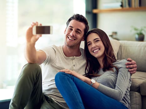 Happy at home with my love. Shot of a happy young couple taking selfies together at home.