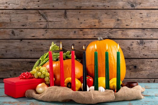 Composition of halloween decoration with candles and pumpkins on wooden background
