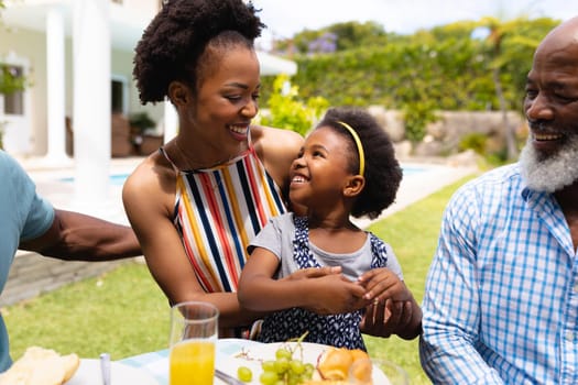 Smiling african american mother and daughter looking at each other during brunch