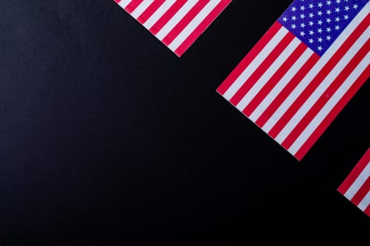 Overhead view of america flags with red and white stripes along with stars over black background