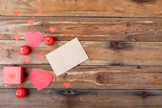 Overhead view of heart shaped decoration by envelope and candles on wooden table, copy space