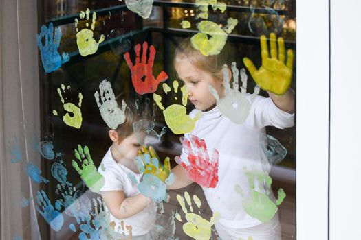 The kids paint with palms on the window. Quarantine