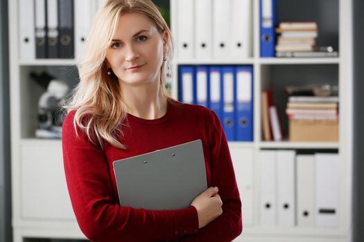 Lovely businesswoman stand with folder in presentable suit, smiling secretary