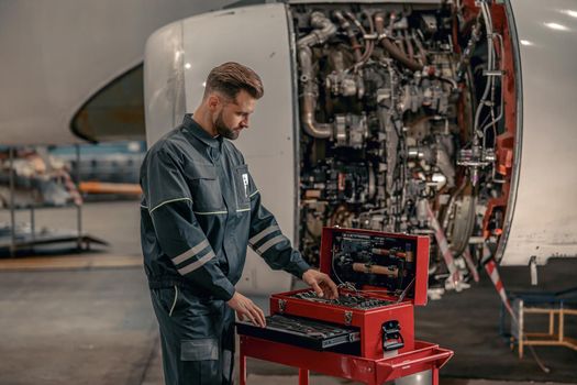 Male airline mechanic using tool box in hangar