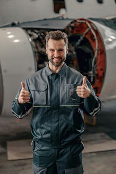 Cheerful airline mechanic showing approval gesture in hangar