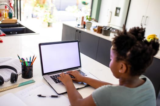 African american girl using laptop while e-learning at home, copy space