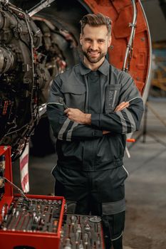 Cheerful aircraft mechanic standing near tool box in hangar