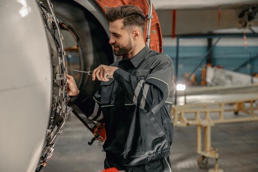 Male aviation mechanic repairing aircraft in hangar