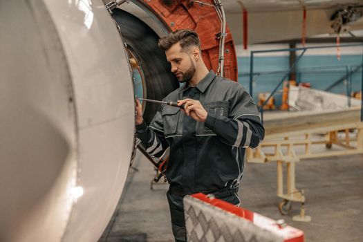 Male aviation mechanic repairing airplane in hangar