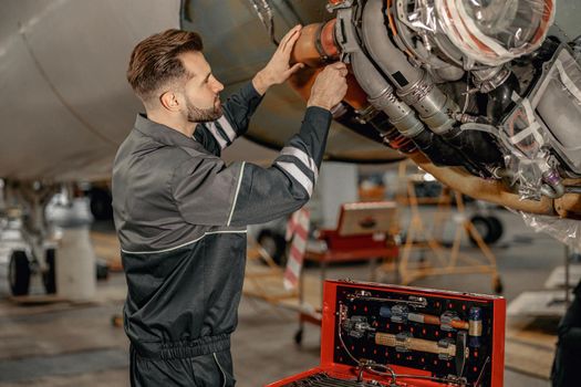Male airline mechanic repairing aircraft in hangar