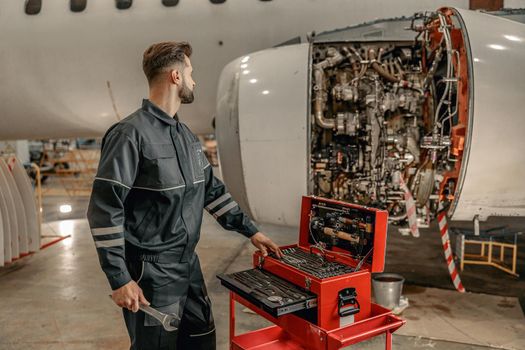 Male aircraft mechanic using tool box in hangar