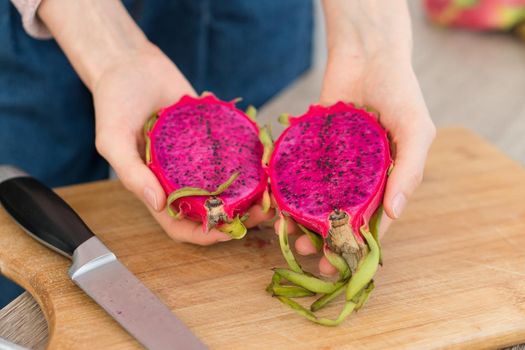 Female hands holding fresh ripe organic dragon fruit or pitaya, pitahaya. Exotic fruits, healthy eating concept