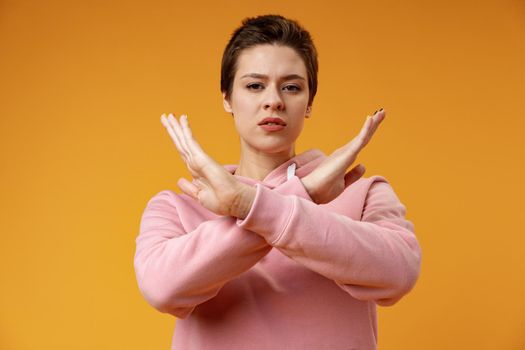Young woman making a rejection gesture on a yellow background