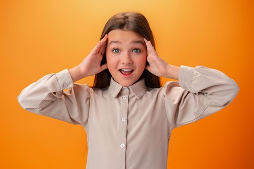 Shocked joyful teen girl against orange background